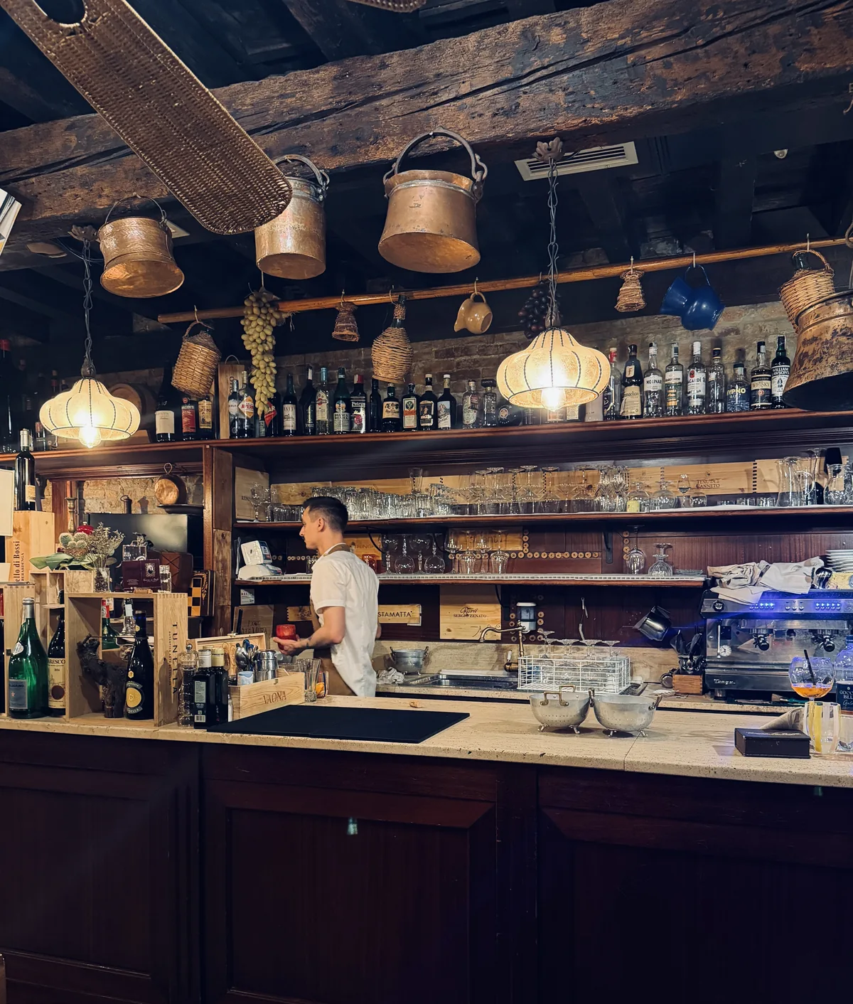 Il banco bar della taverna con travi in legno e lanterne di rame