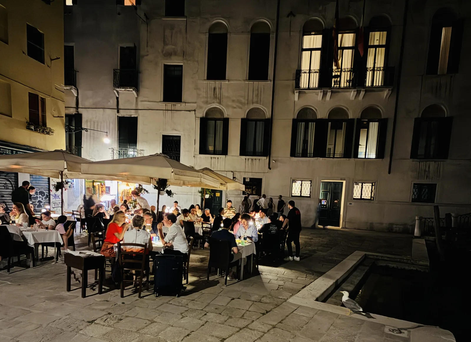 I tavoli della Taverna da Baffo nel Campiello Sant'Agostin di notte, con il palazzo illuminato alle spalle